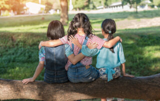 Girls in the park hugging each other, facing the park