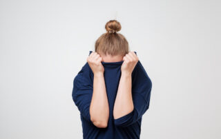 Woman hiding face under her clothes