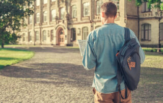 Young male student walking around college campus holding map